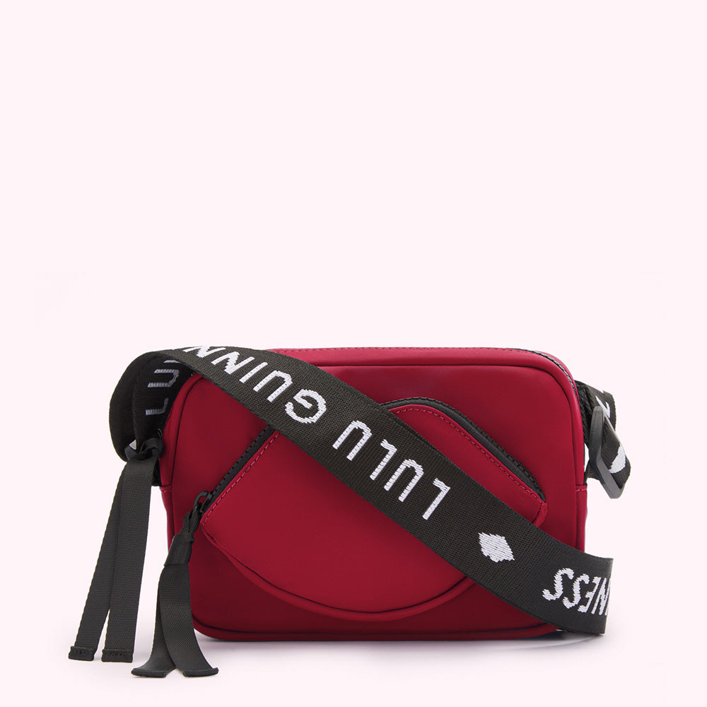 Red crossbody bag with a lip-shaped detail and a black strap with white "Lulu Guinness" lettering.