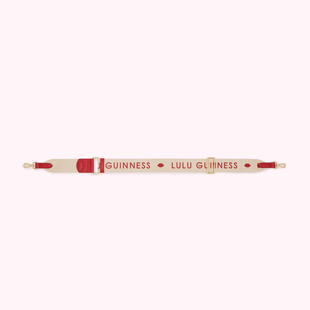 Beige and red Lulu Guinness shoulder strap with the brand name printed on it.