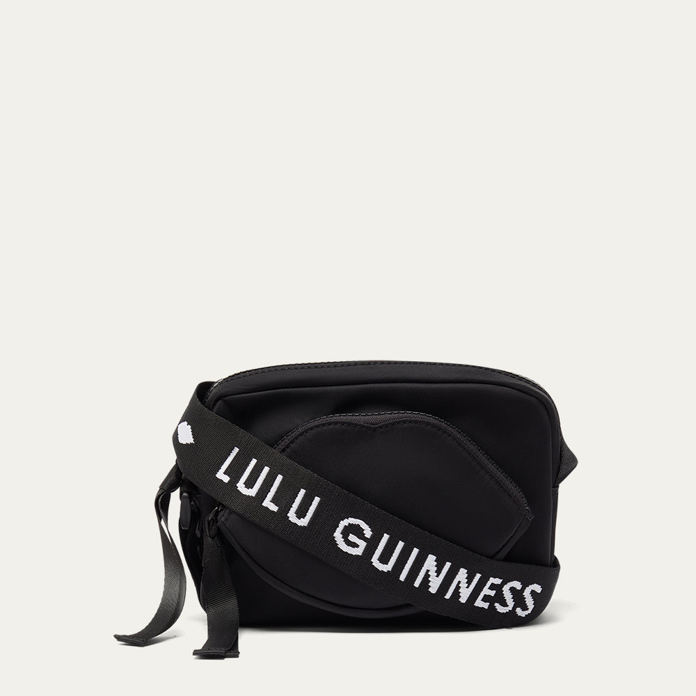 Black bag with 'Lulu Guinness' branded strap on a light grey background