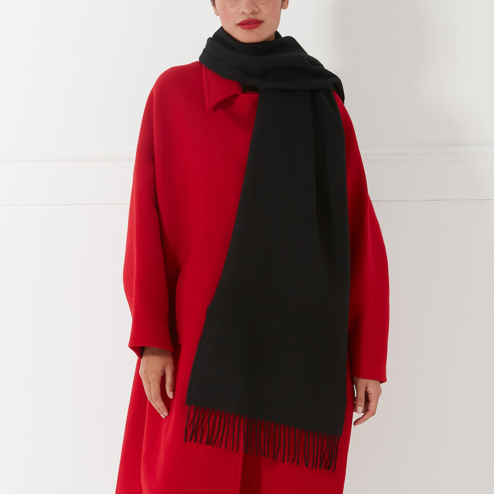 Close-up of a woman wearing a long red coat and a black fringed scarf.