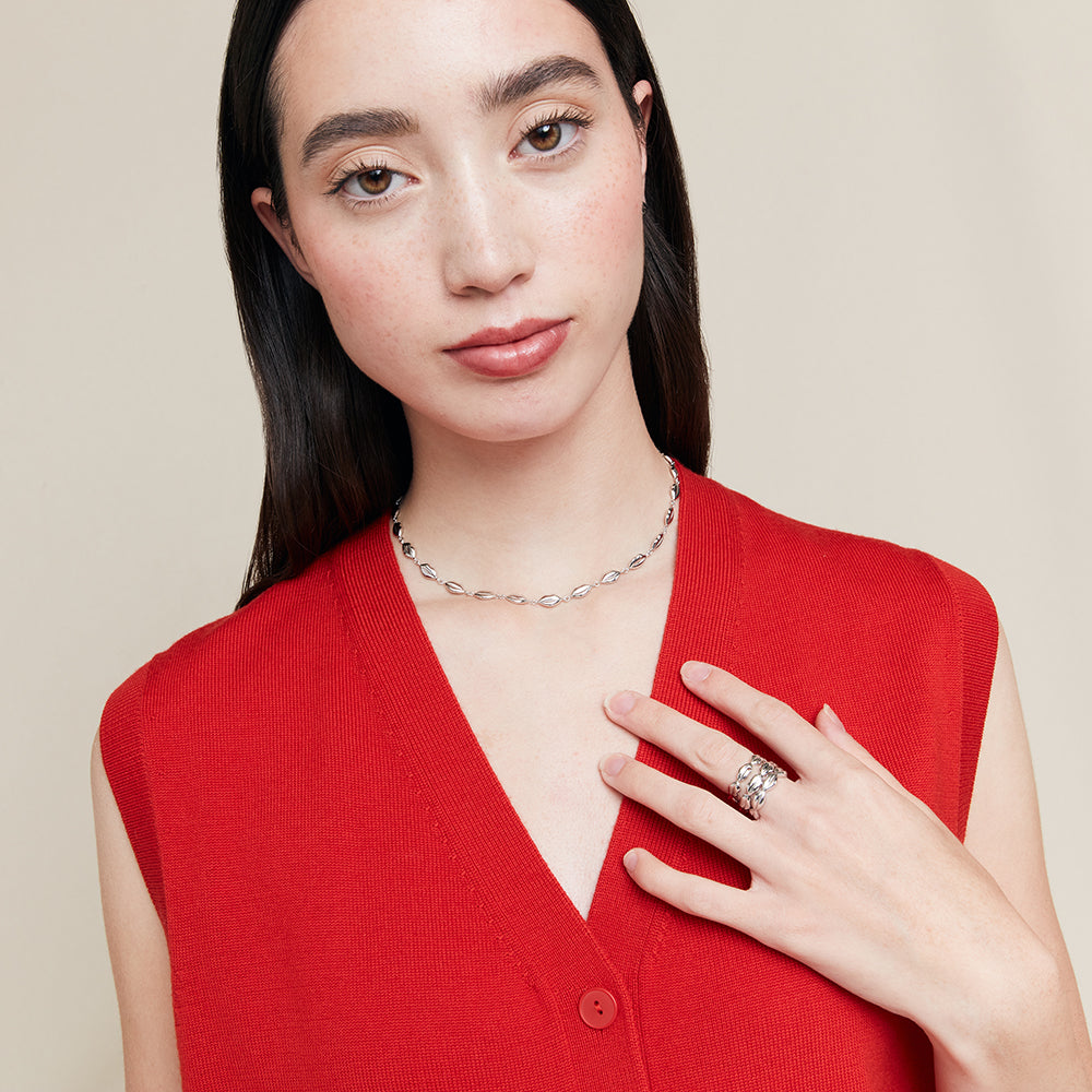 Woman wearing a red sleeveless top and silver jewelry on a beige background