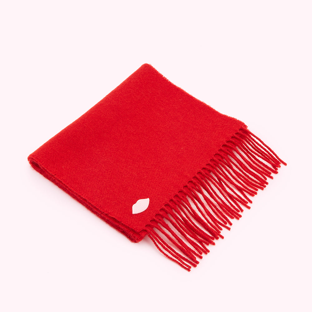 Red fringed scarf with a small white logo.
