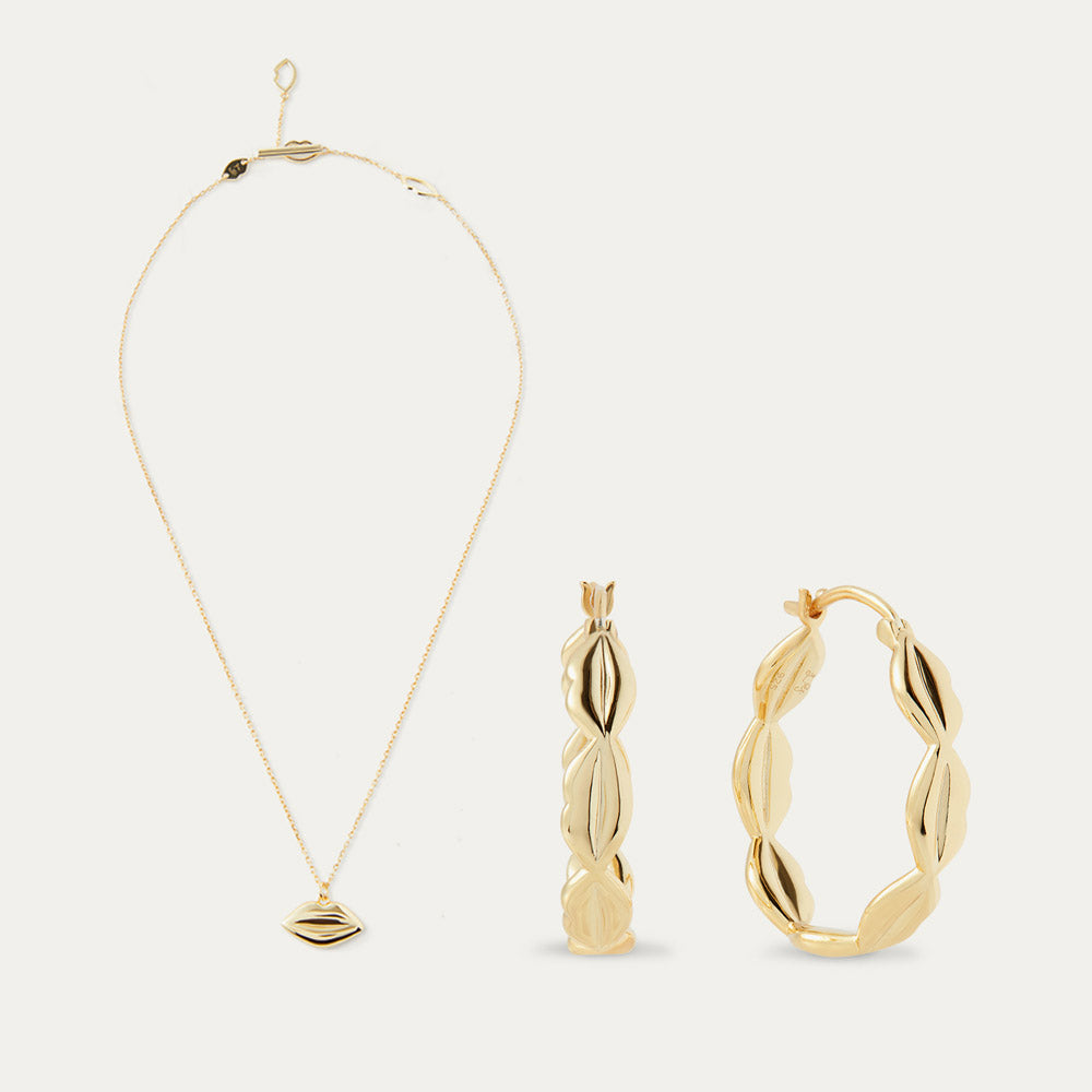 Gold necklace, pendant, and hoop earrings on a white background