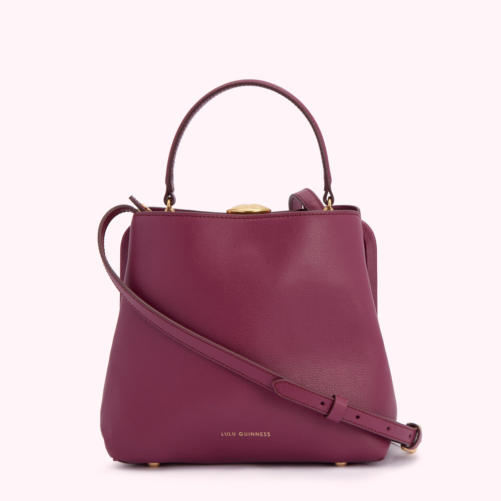 A burgundy Lulu Guinness handbag with a top handle and a crossbody strap. The bag has gold hardware.