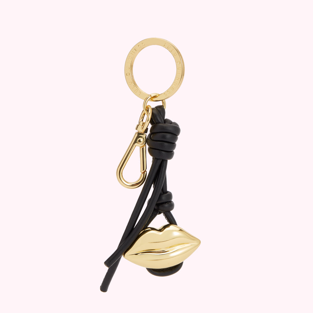 Gold lip-shaped keychain with black leather accents.