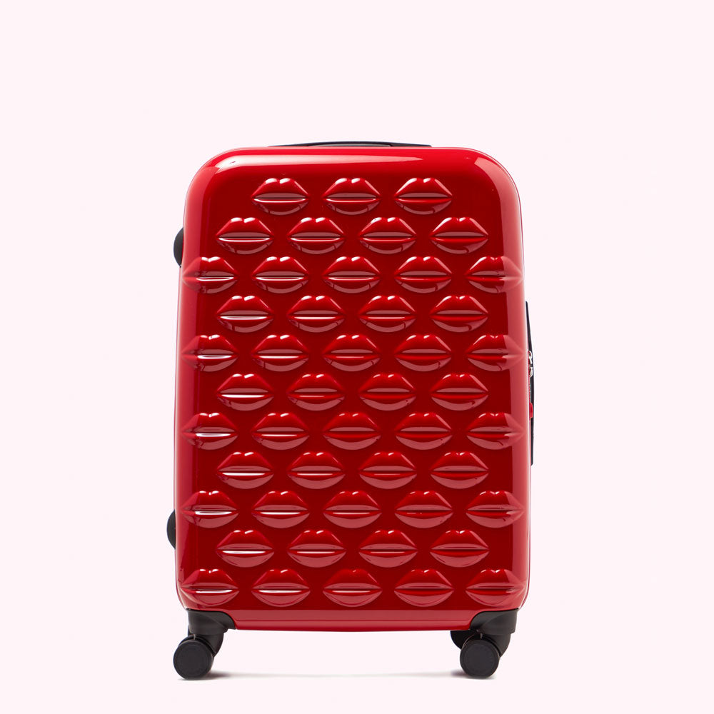 Red suitcase with a lip print pattern against a white background.