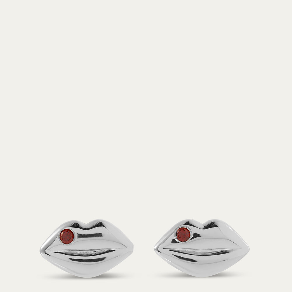 Silver lip-shaped earrings with red stones on a white background