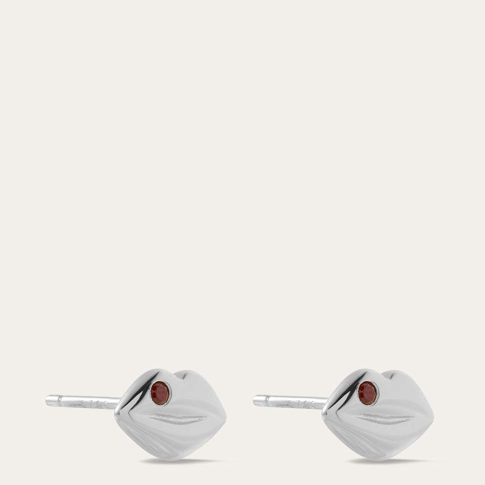 Pair of silver lip-shaped earrings with red gemstones on a white background