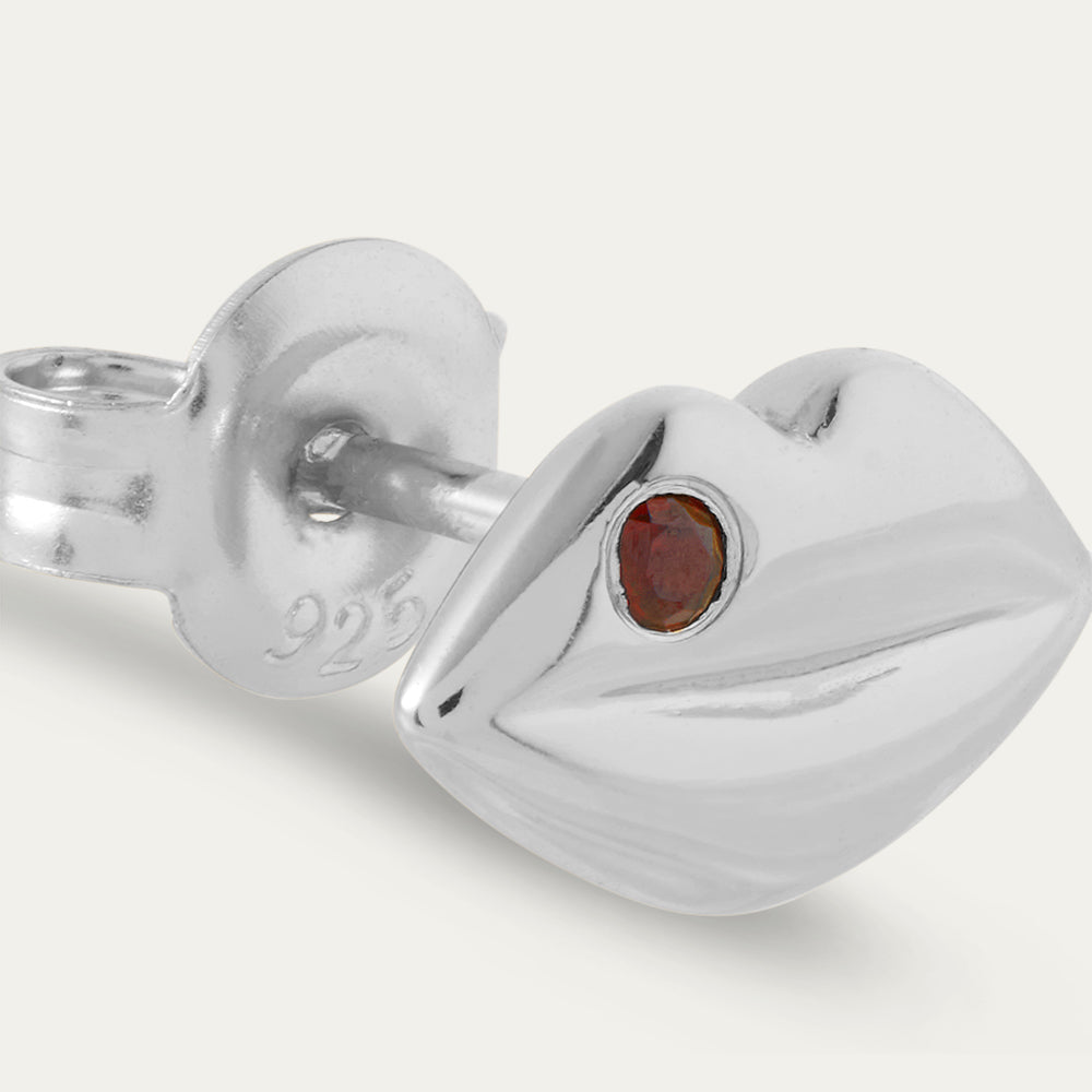 Silver earring with a red gemstone on a white background