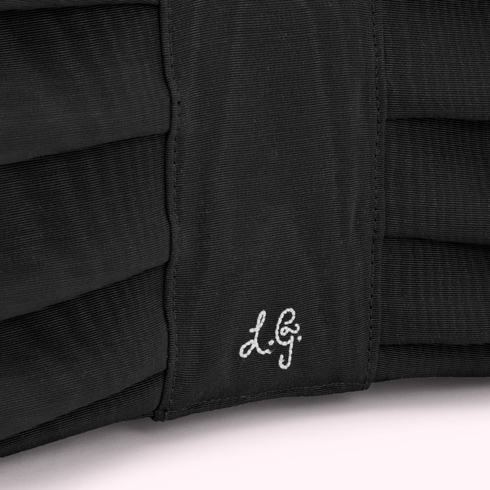 Close-up of a black fabric item with the initials "L.G." embroidered on it.
