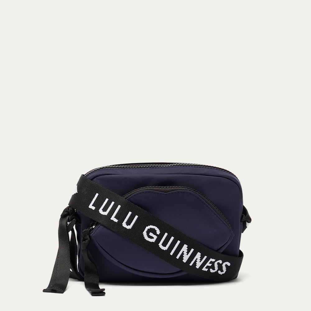 Navy blue bag with a black strap featuring 'Lulu Guinness' on a light grey background