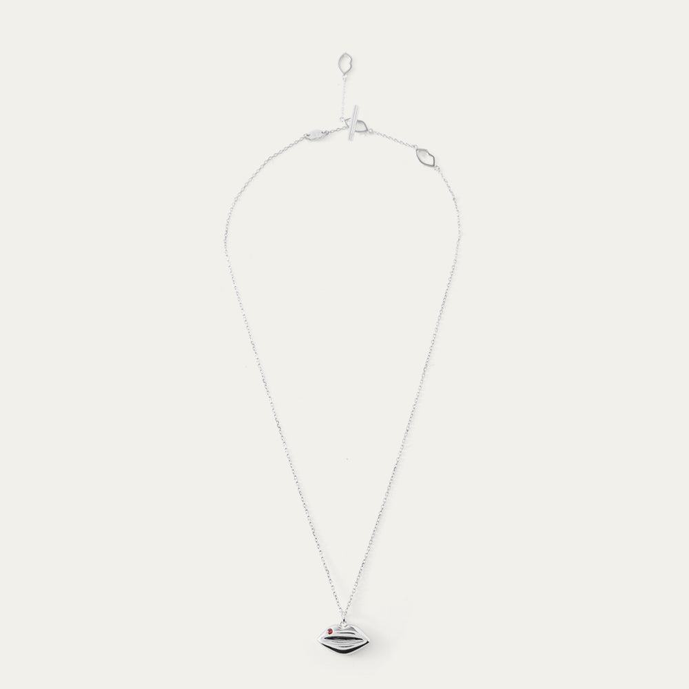 Silver and ruby necklace with a lip-shaped pendant on a white background