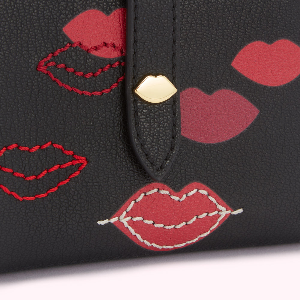 Close-up of a black leather wallet with red lips pattern, some lips are embroidered.