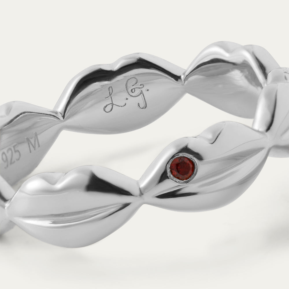 Silver ring with a red gemstone on a white background