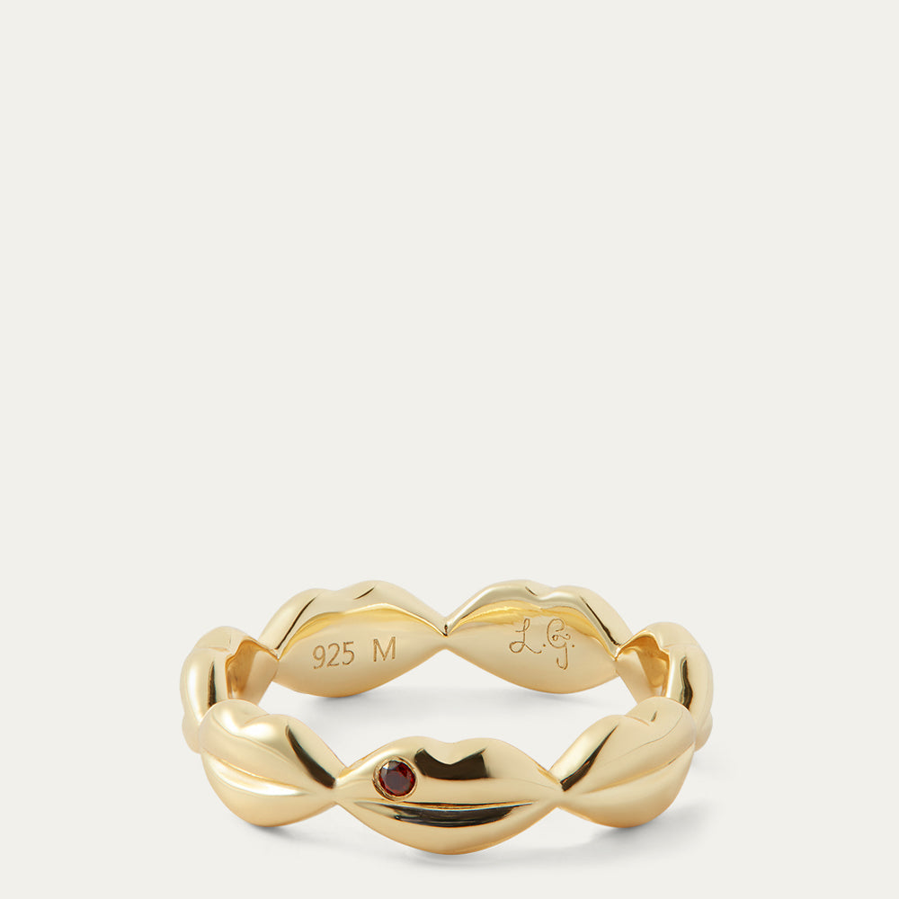 Gold ring with a red gemstone on a white background