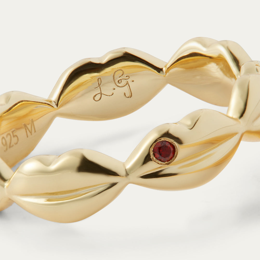 Gold ring with a red gemstone on a white background