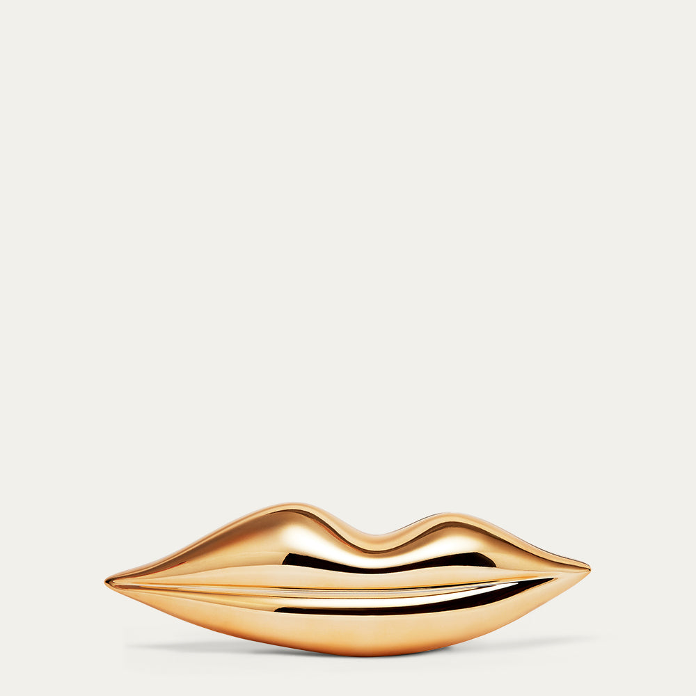 Gold lip-shaped clutch bag on a beige background