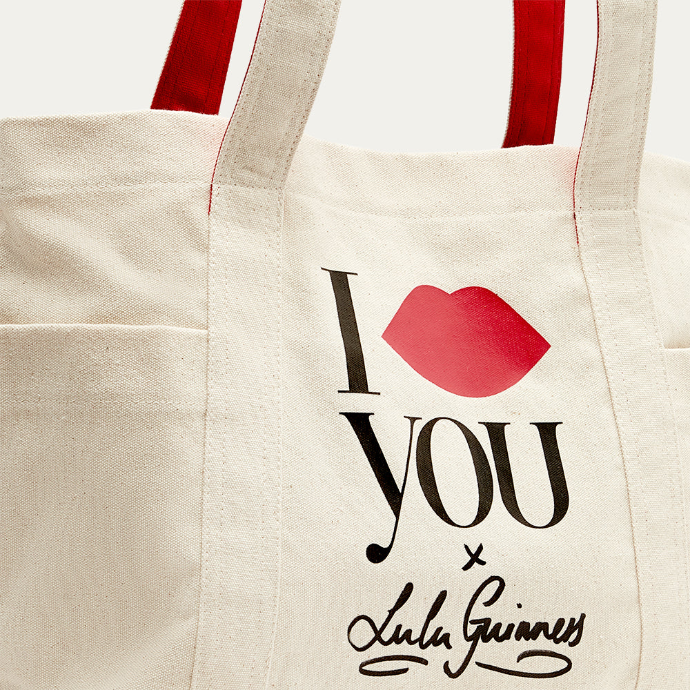 Beige tote bag with 'I Lip YOU x Lulu Guinness' and a red lip print, featuring Lulu Guinness branding.