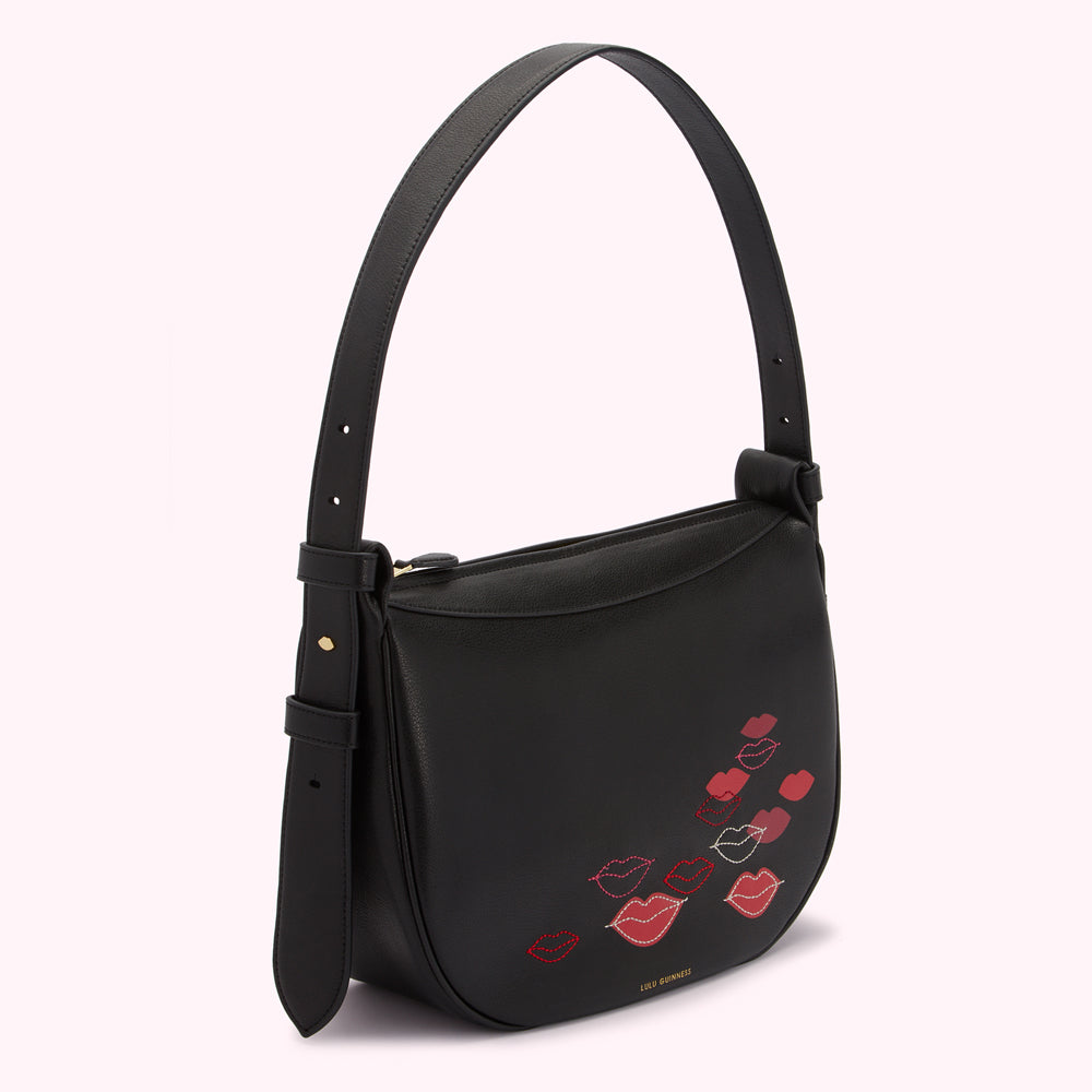 Black leather Lulu Guinness shoulder bag with red and pink lip embroidery.
