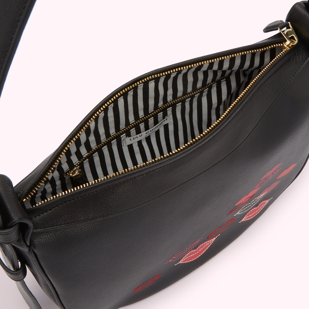 Black leather Lulu Guinness shoulder bag with red lips embroidery, gold zipper, and black and white striped interior.