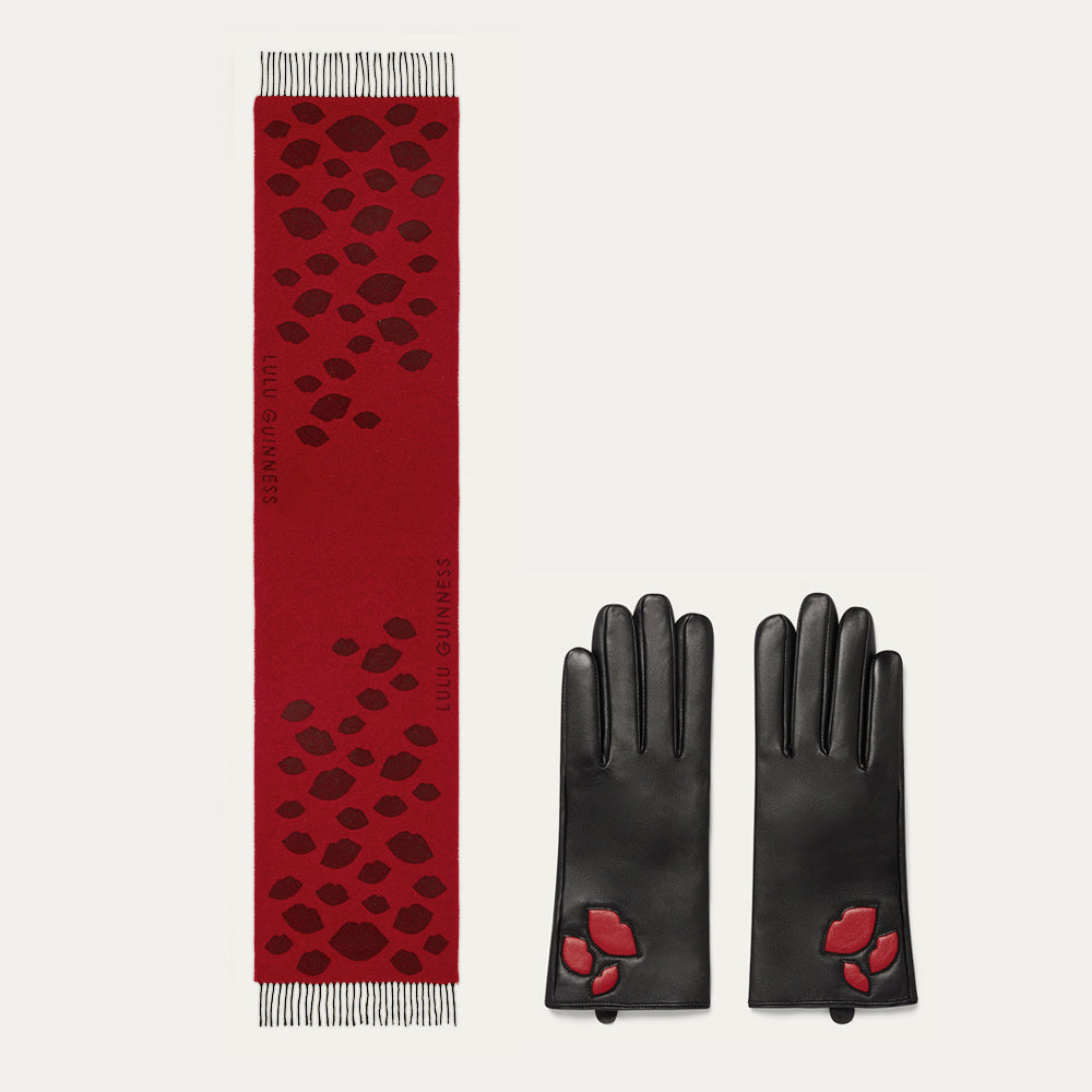 Red wool scarf with black lip pattern and black leather gloves with red lip details on a light gray background