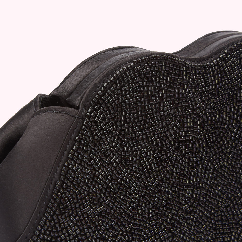 Close-up of a black beaded bag, showcasing the texture of the beads and the satin fabric.
