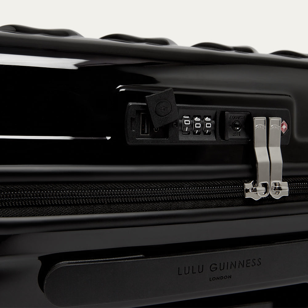Black suitcase with Lulu Guinness branding on a white background