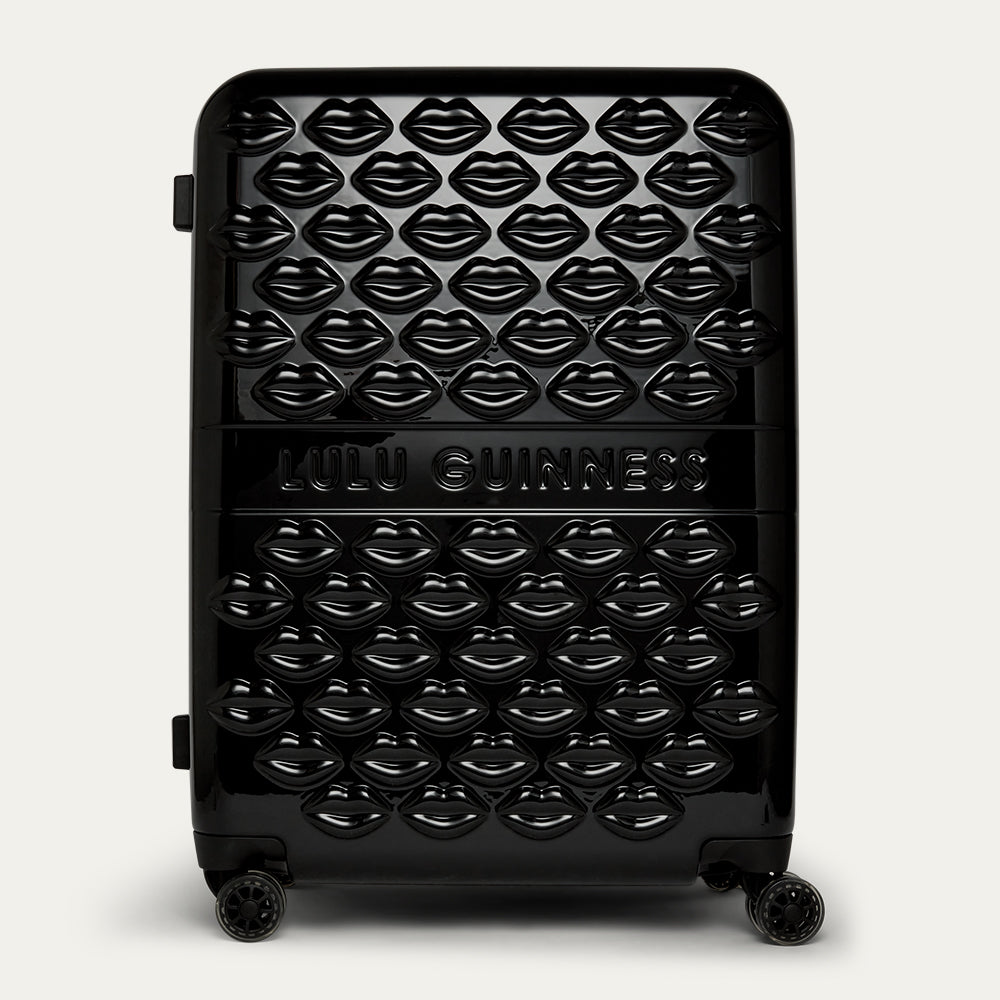 Black suitcase with lip pattern and 'Lulu Guinness' branding on a white background