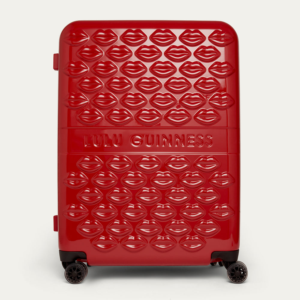 Red suitcase with lip pattern and 'Lulu Guinness' branding on a white background