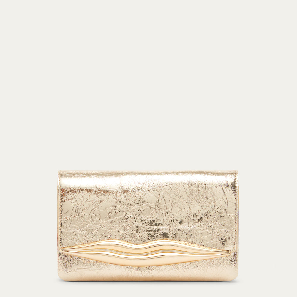 A metallic gold clutch bag with a textured, cracked leather finish and a wavy gold-tone accent across the front, set against a solid off-white background.