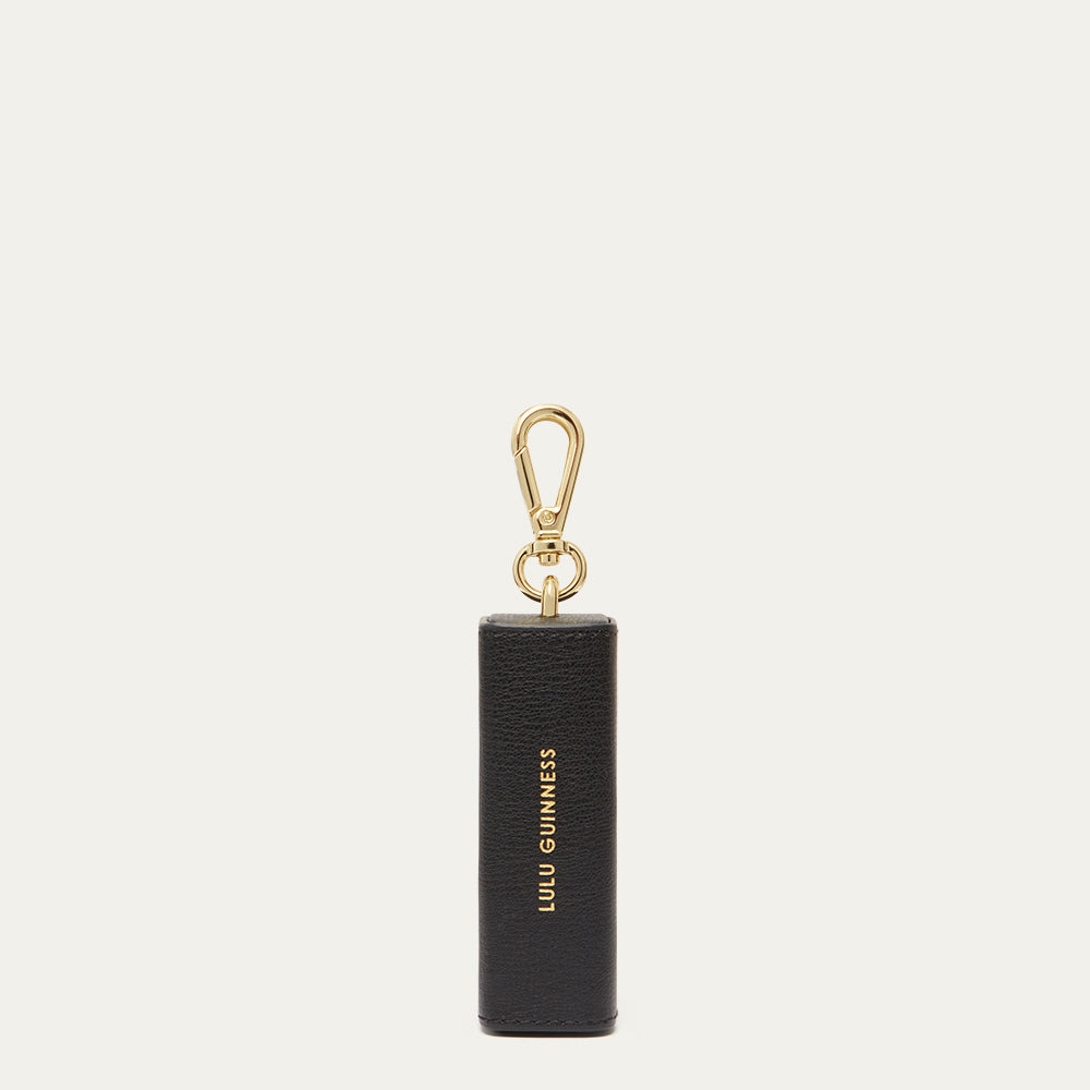 Black keychain with gold clasp and 'Lulu Guinness' logo on a light beige background