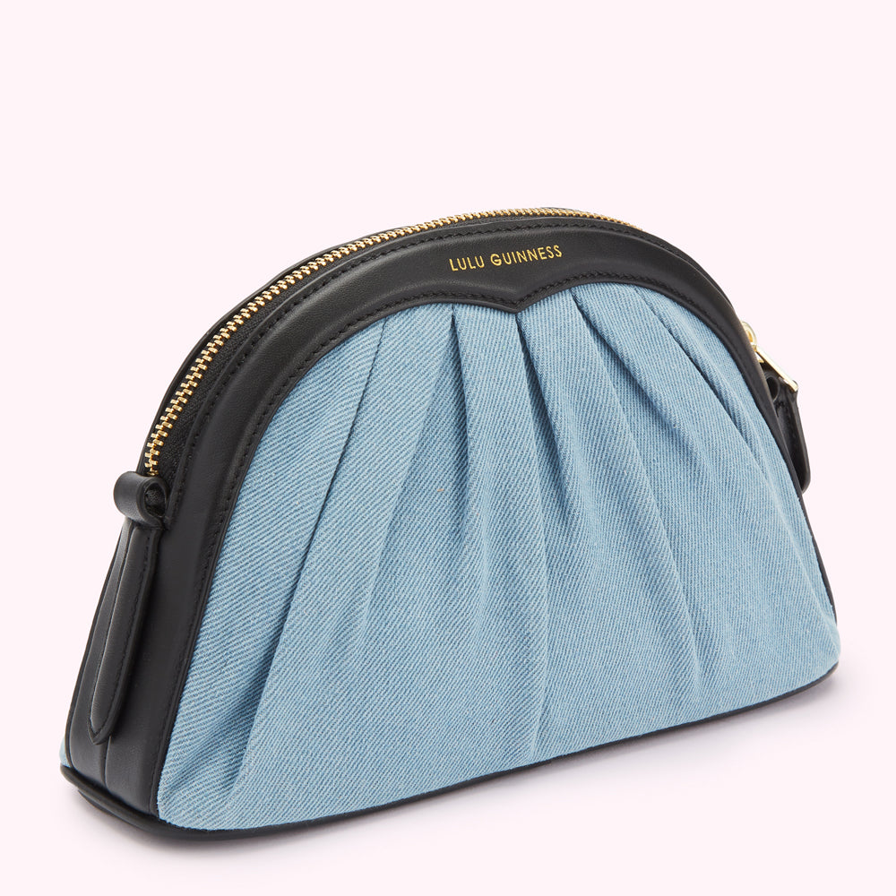 Light blue denim Lulu Guinness pleated crossbody bag with black leather trim and gold zipper.