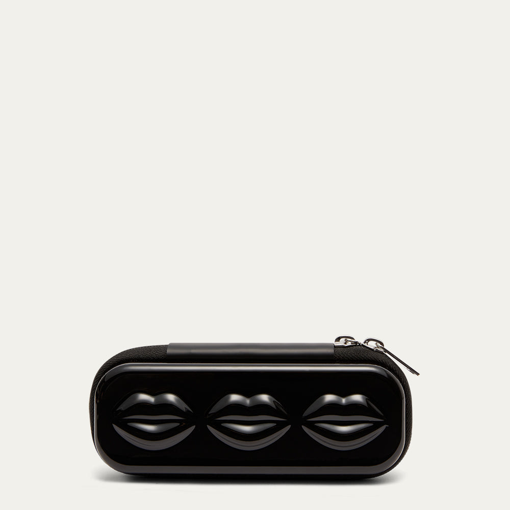 Black sunglasses case with lip details and silver zips on a grey background.
