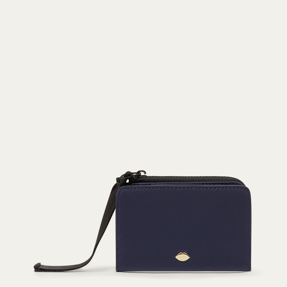 Navy blue wallet with a black ribbon zip pull on a light grey background