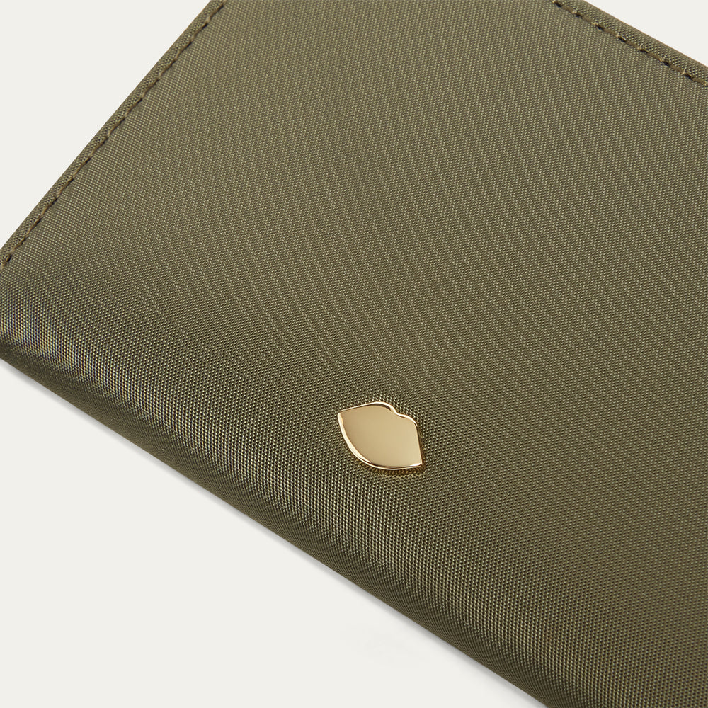 Close up image of a gold lip pin on a nylon green wallet.