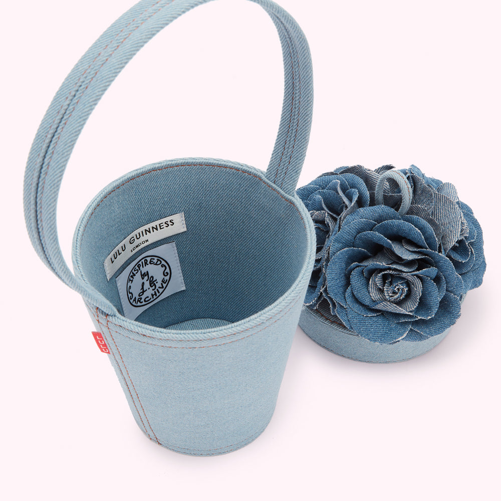 Light blue denim bucket bag with a matching denim rose detail. The bag is labelled Lulu Guinness London.
