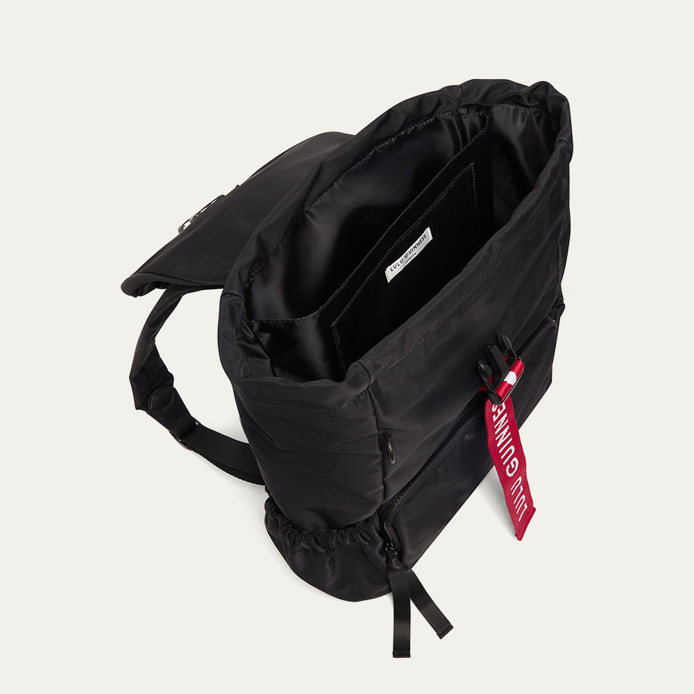 Black Lulu Guinness backpack with red logo detail, viewed from above, showing the inside of the bag.