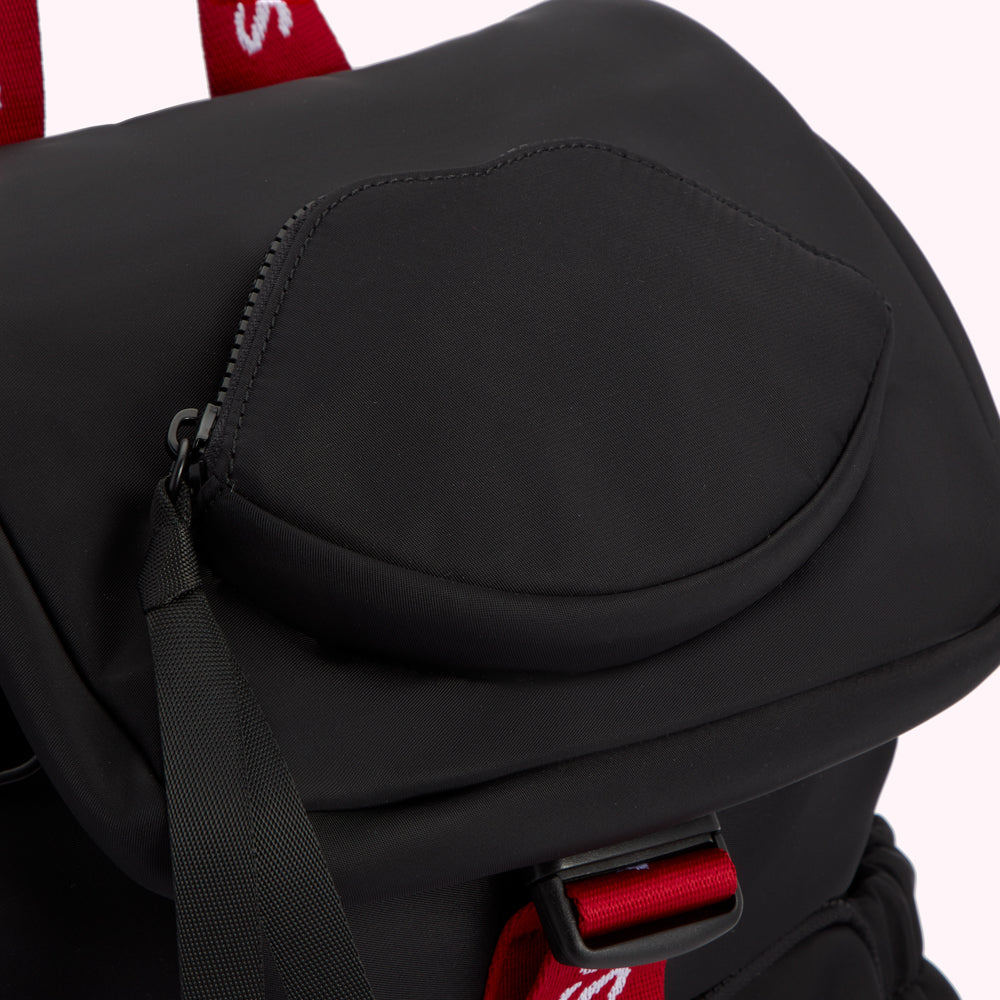 Close-up of a black backpack with a lip-shaped pocket and red accents.