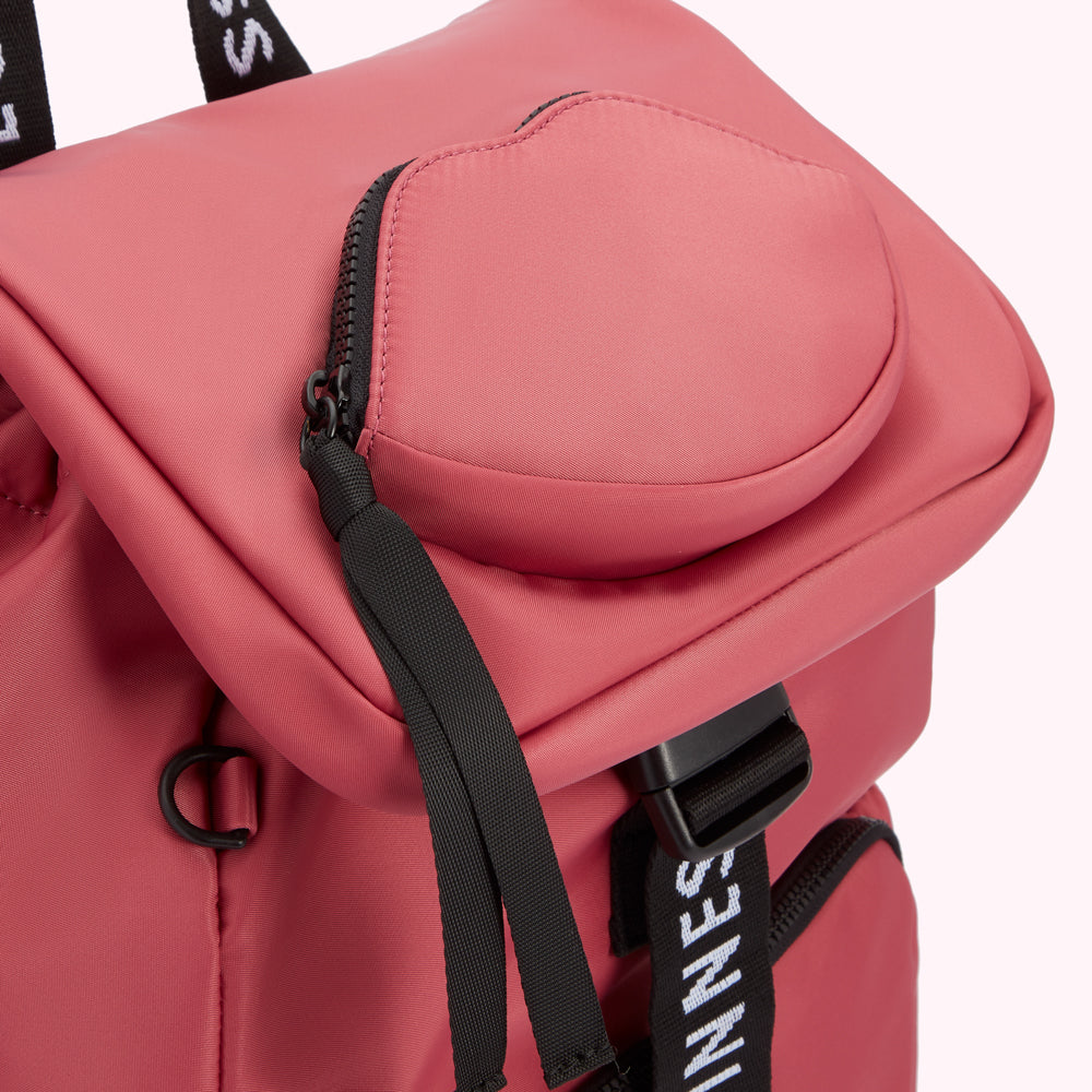 Close-up of a dusty rose-coloured backpack with a heart-shaped zippered pocket and black accents.