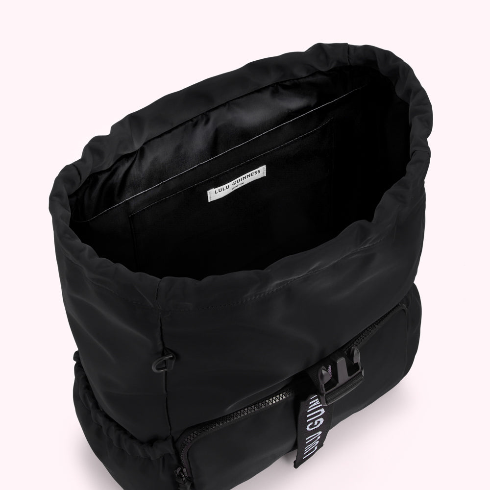 Inside view of a black Lulu Guinness backpack with drawstring closure and brand label.