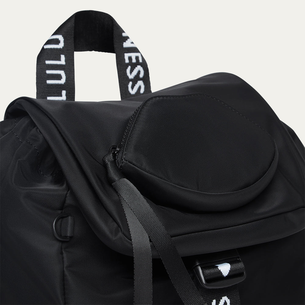 Black backpack with visible branding and a lip-shaped pocket on a light grey background