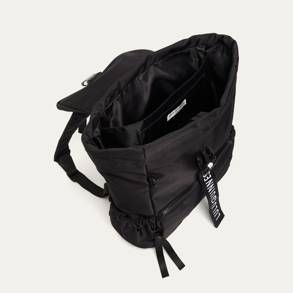 Black backpack open showing a black lining on a light grey background