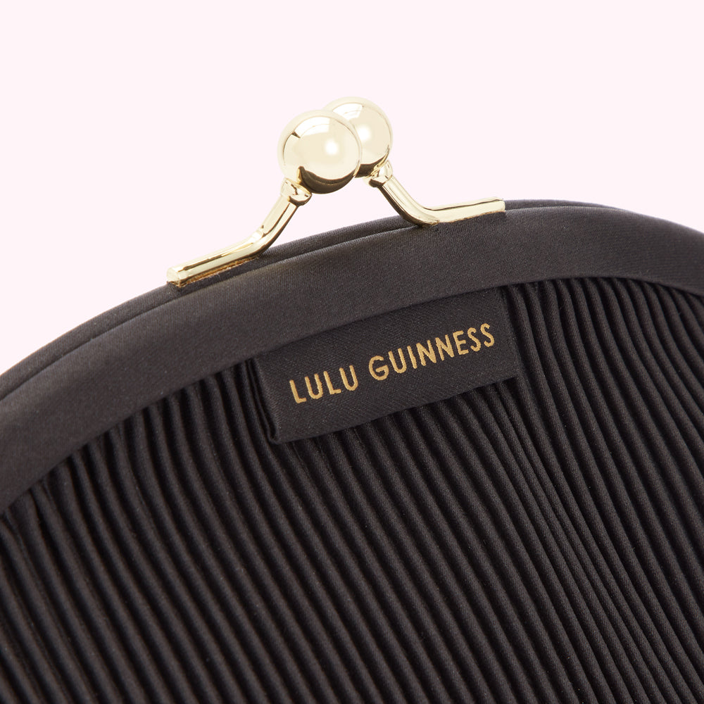 Close-up of a black Lulu Guinness pleated purse with gold clasp.
