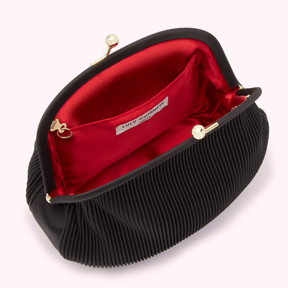 Open black pleated Lulu Guinness clutch with red satin lining.