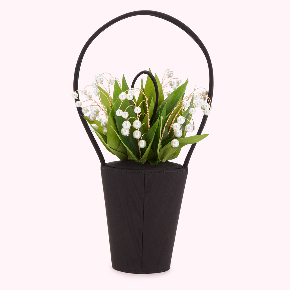 Black handbag shaped like a vase with a bouquet of lily of the valley and pearls.
