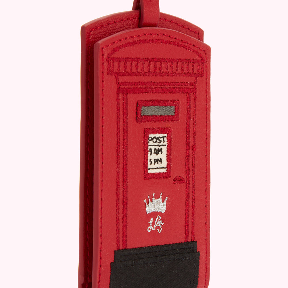Red leather luggage tag shaped like a British postbox.