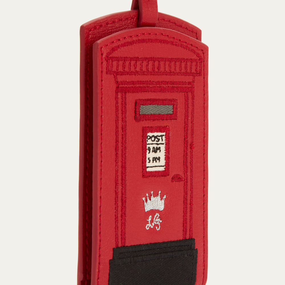 Red leather luggage tag shaped like a British postbox.