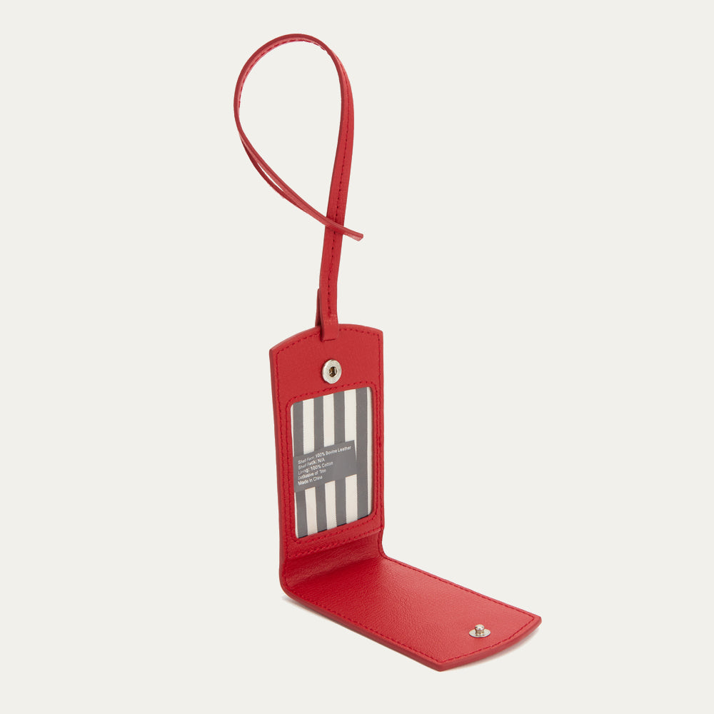 Red leather luggage tag open to reveal a black and white striped interior with product information.