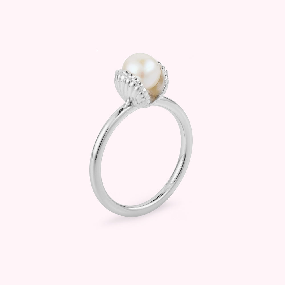 Sterling silver shell shaped ring with a freshwater pearl on a white background.