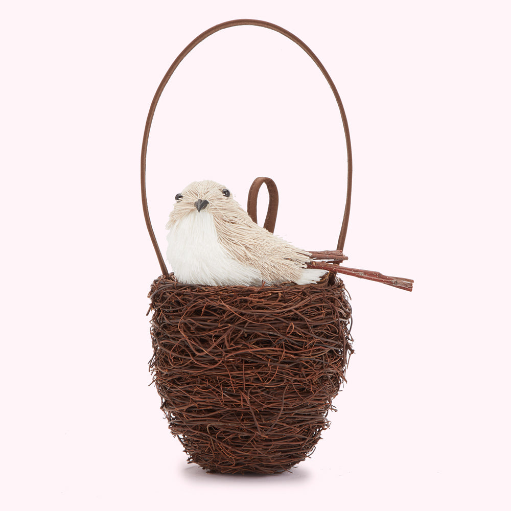 Brown Lulu Guinness bird nest handbag with a beige bird sitting in a brown twig nest hanging from a brown handle. The background is white.

